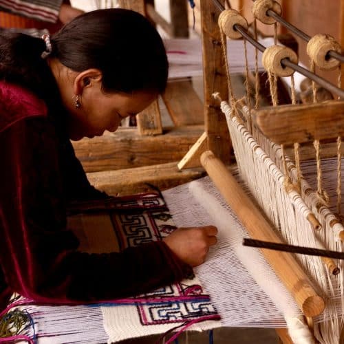 A Sumbanese woman working on a traditional loom to create ikat textiles.