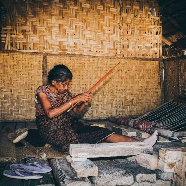 Elderly woman weaving traditional Sumbanese Tenun Ikat fabric on a handloom