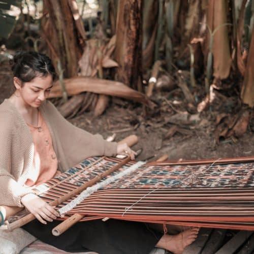 A young woman weaving ikat fabric on a backstrap loom in Sumba.