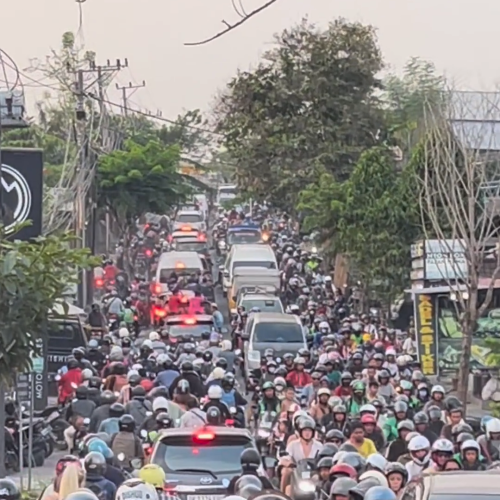 Severe traffic jam in Canggu, Bali, with hundreds of motorbikes and cars filling the street.