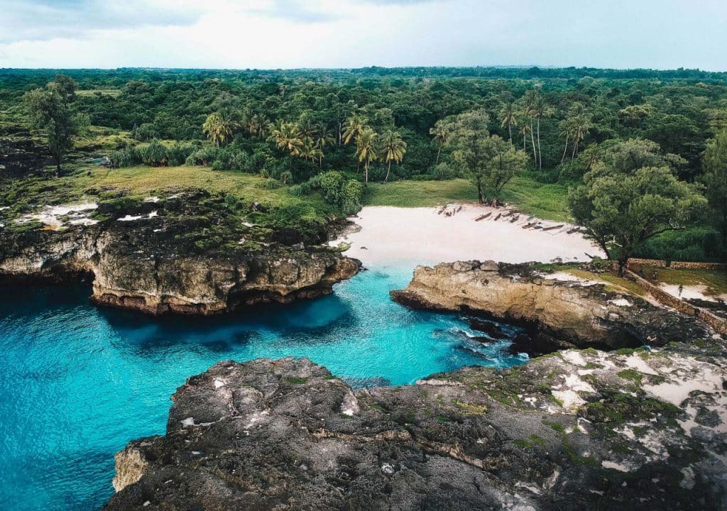 Secluded turquoise cove with cliffs and tropical forest in Sumba, Indonesia.